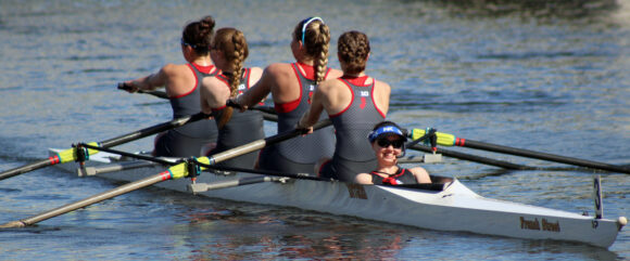 Stephanie Welsh in front of crew shell with team rowers
